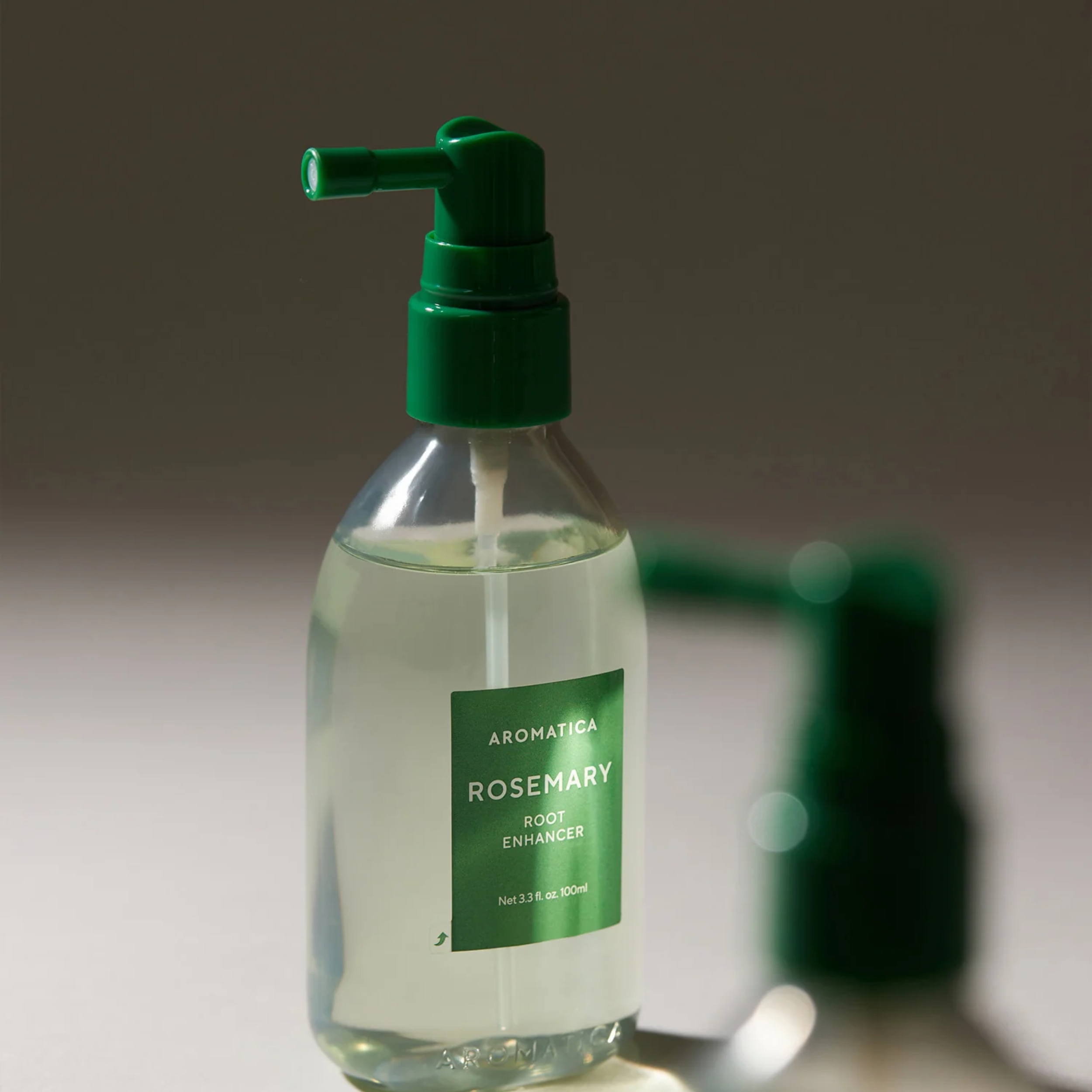 Clear bottle with green pump and label on a neutral background