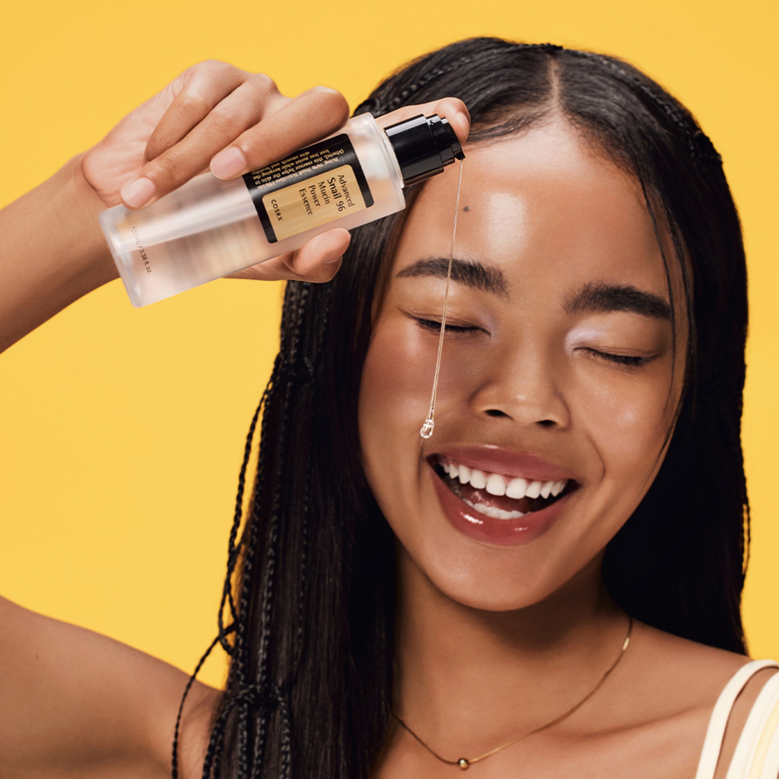 Woman applying a skincare product to her face with a yellow background