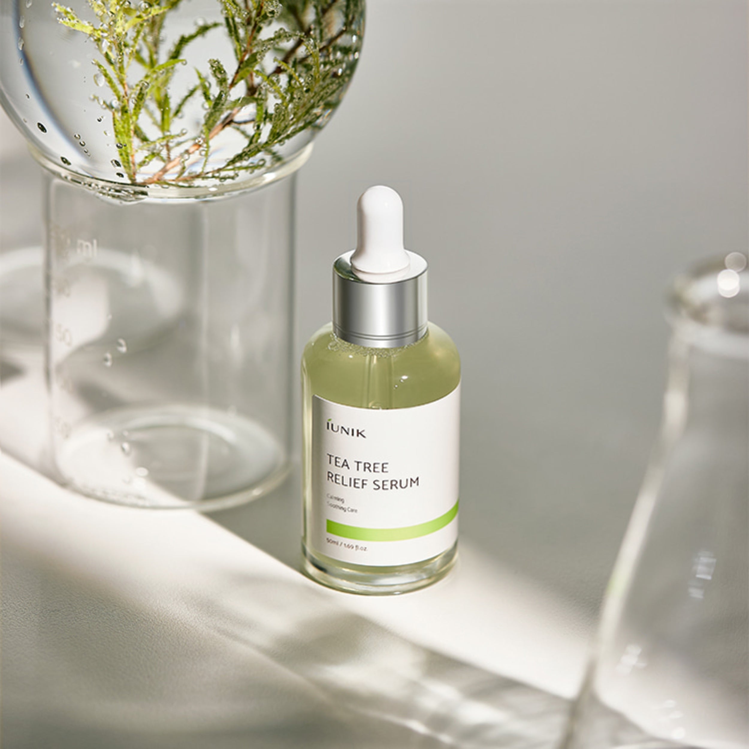 Tea tree relief serum bottle with dropper on a neutral background