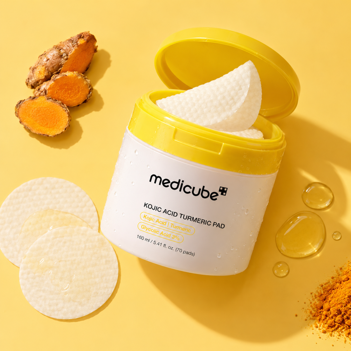 A jar of medicube Kojic Acid Turmeric Pads with the lid open, showing white textured pads inside. The jar is white with a bright yellow lid.