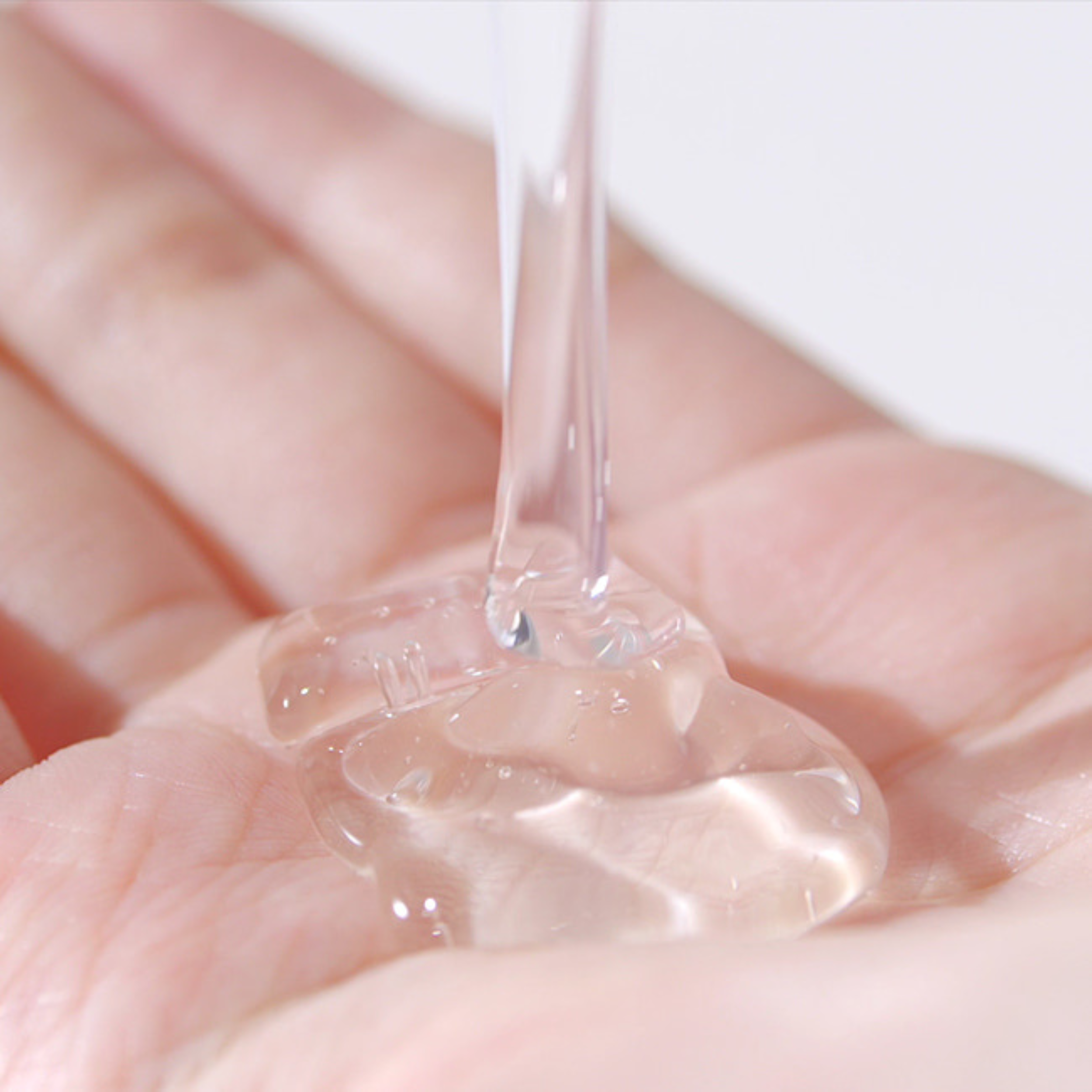 Clear gel being dripped onto a hand with a white background