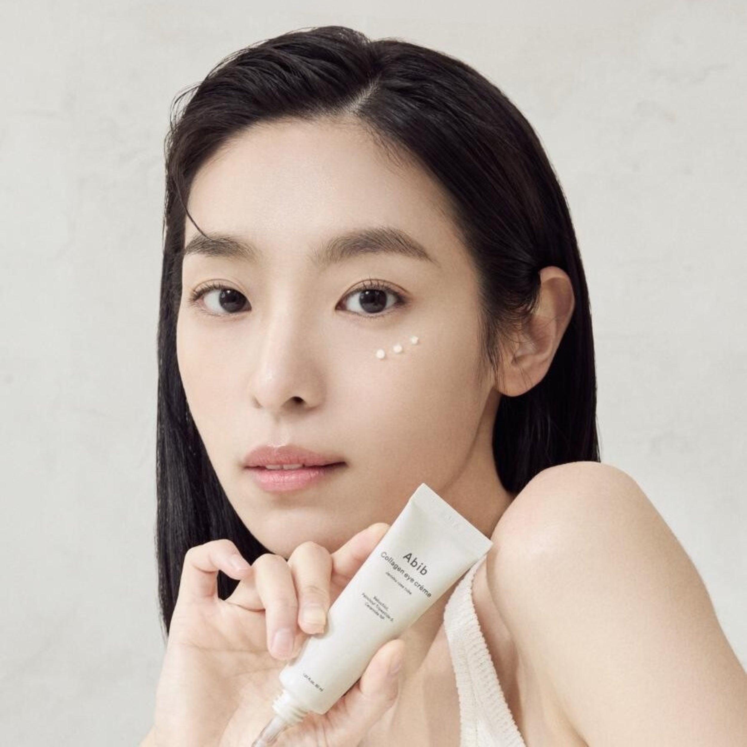 Woman holding Abib Collagen Eye Cream under eyes for hydration