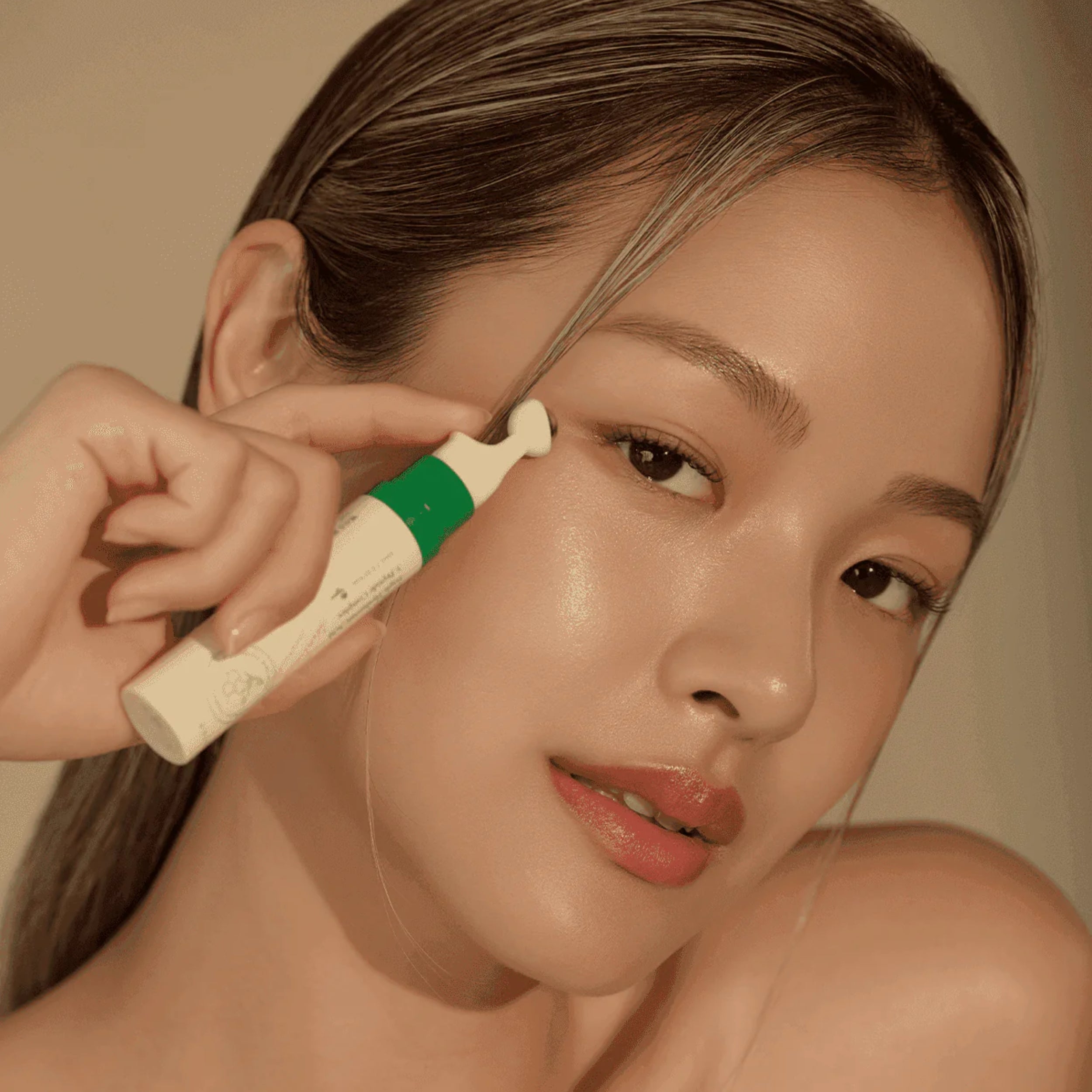 Person applying a cosmetic product to their face with a neutral background