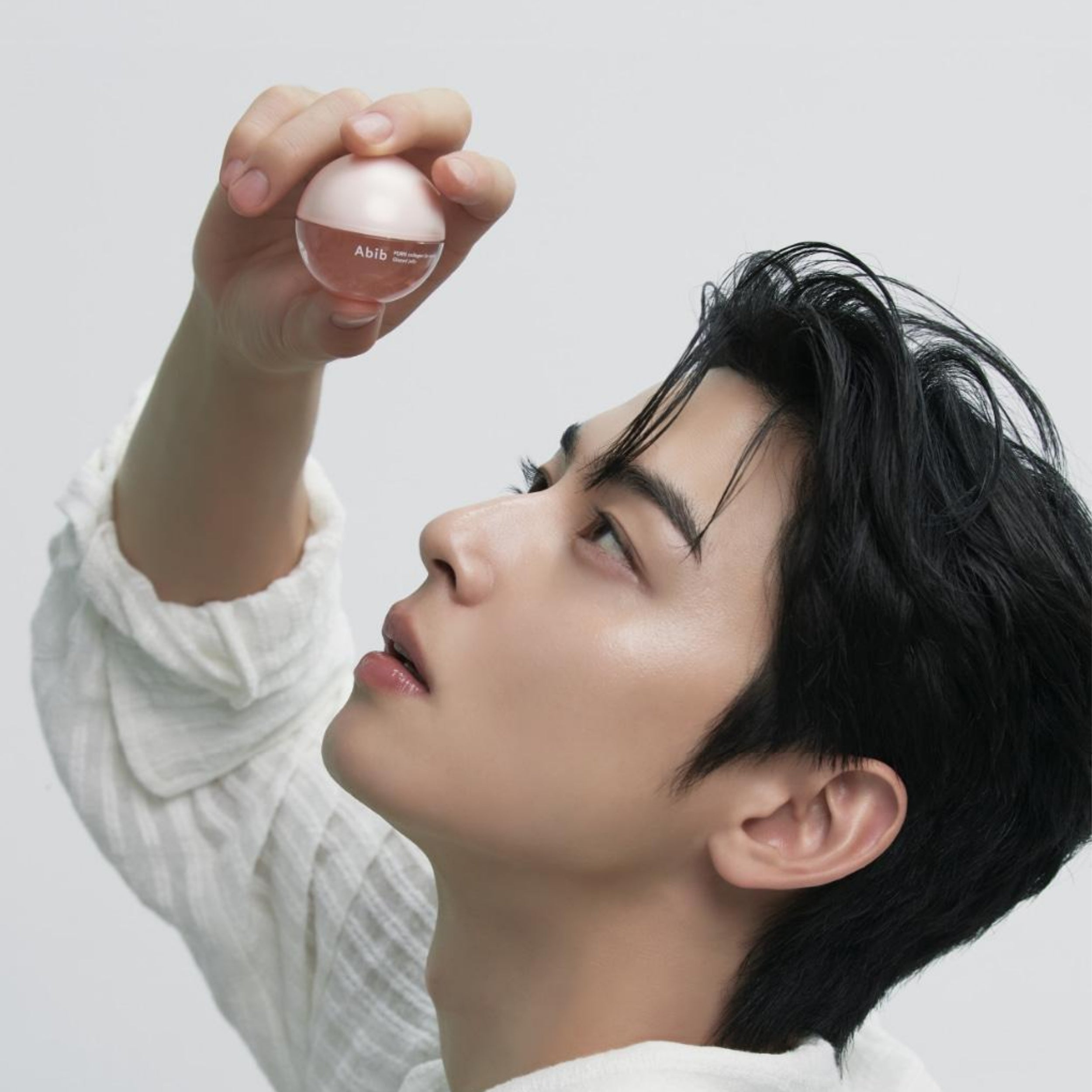 Person holding a pink Abib lip mask against a light background