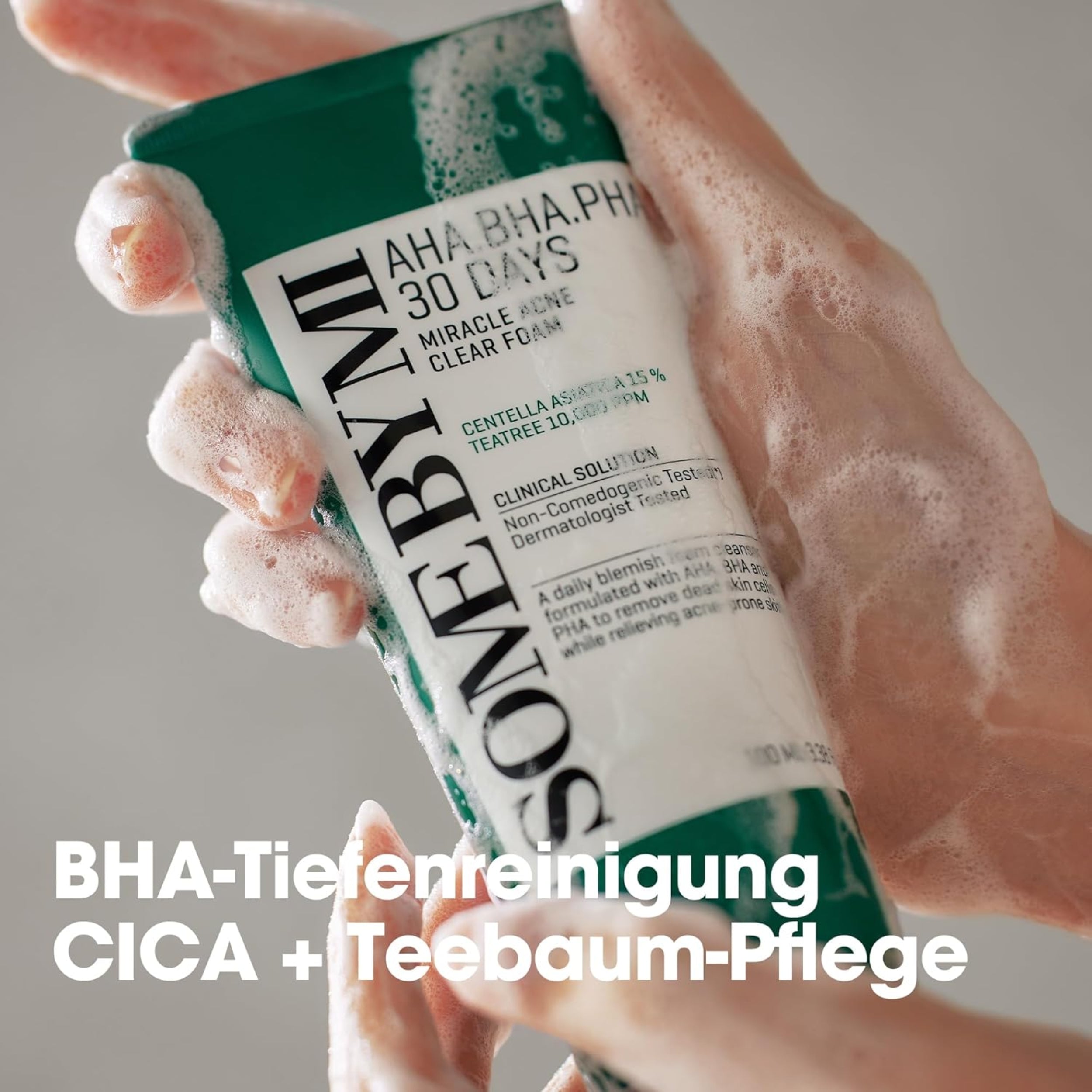 Hand holding a skincare product with visible foam, brand name 'Some By Mi' on a neutral background.