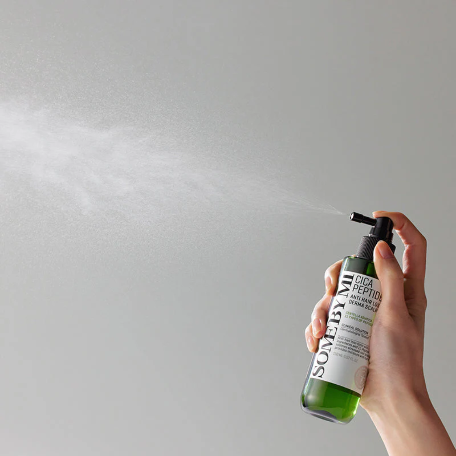 Hand holding a bottle of Sonebye skincare product against a gray background