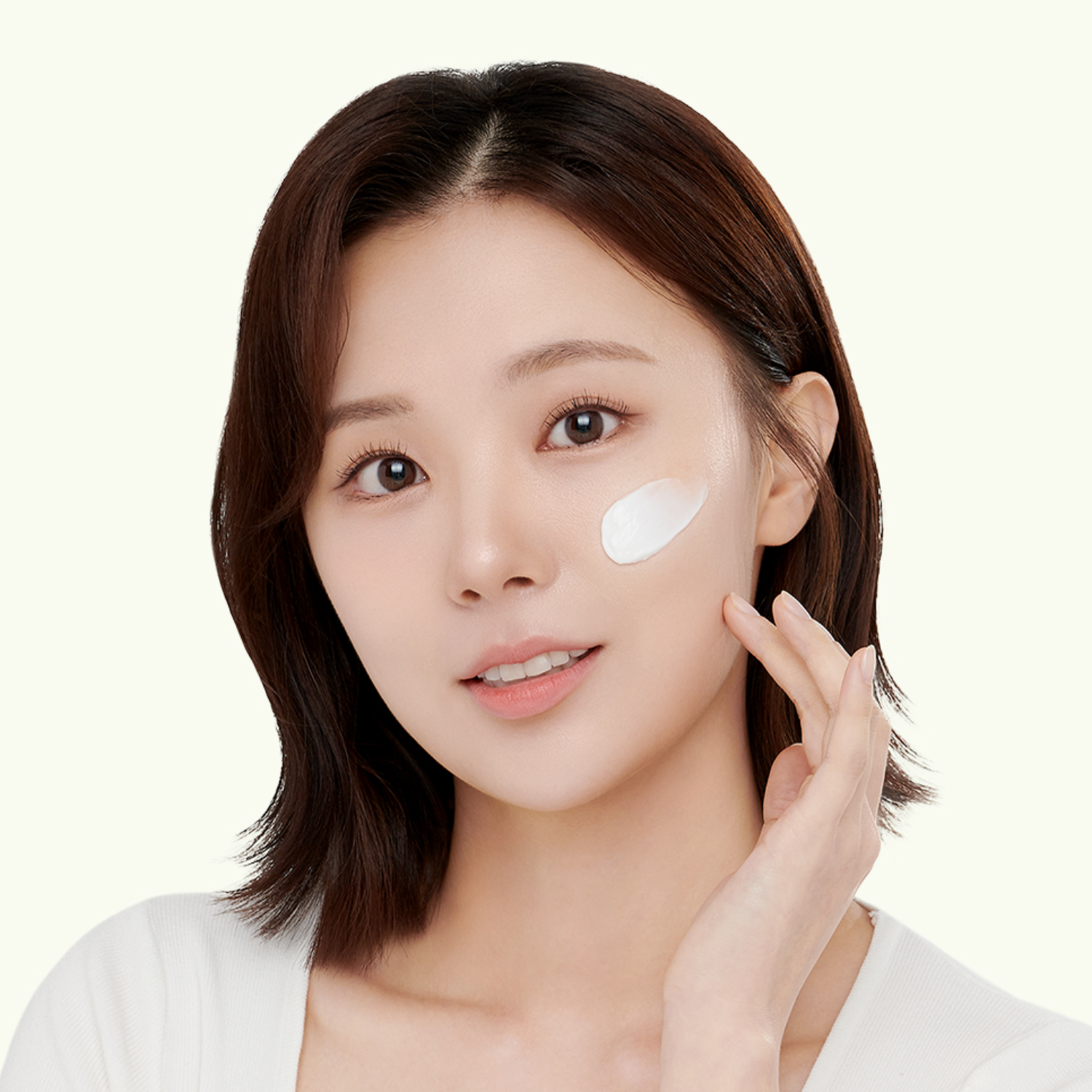 Woman applying cream to her face on a white background