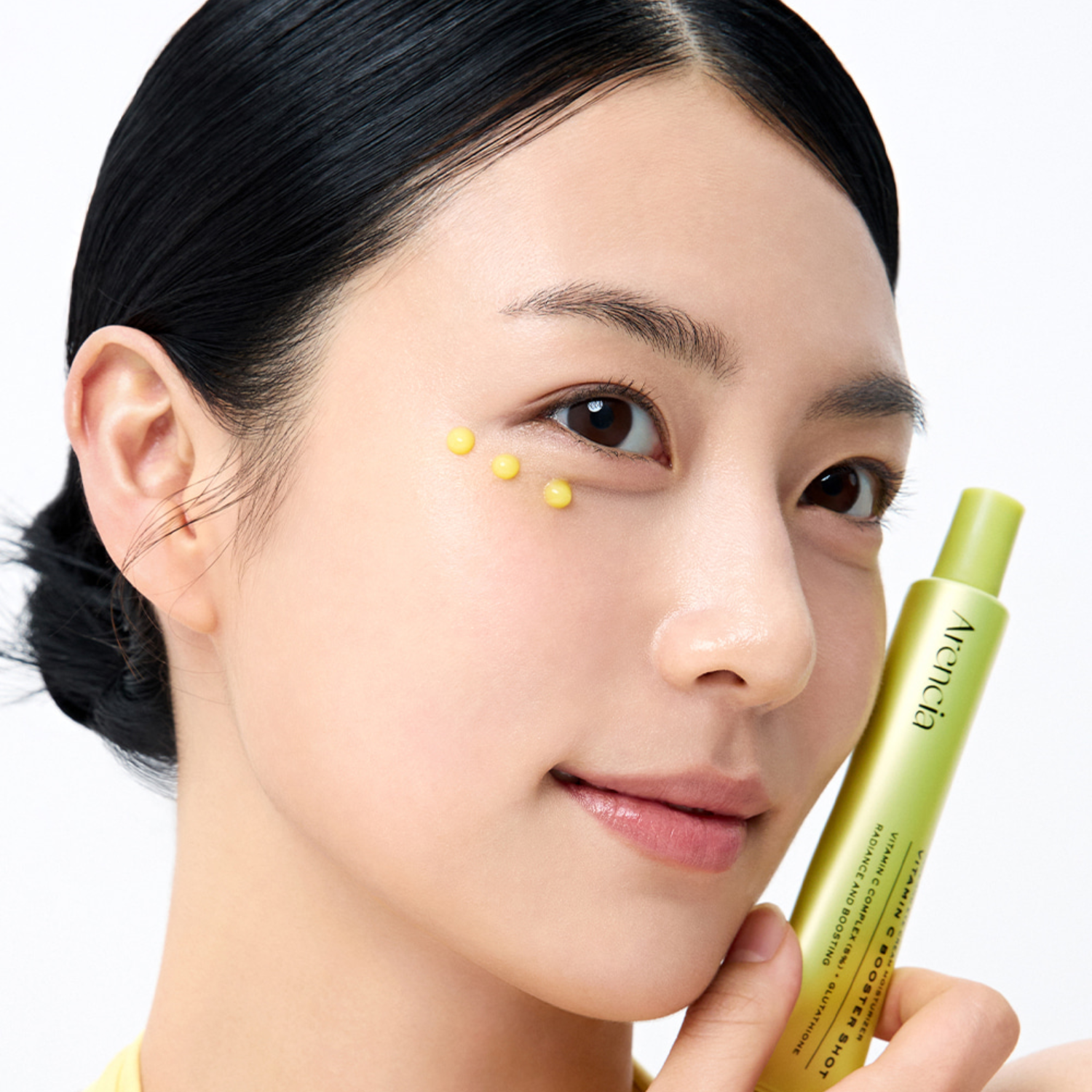 Woman holding a green skincare product with a close-up of her face.