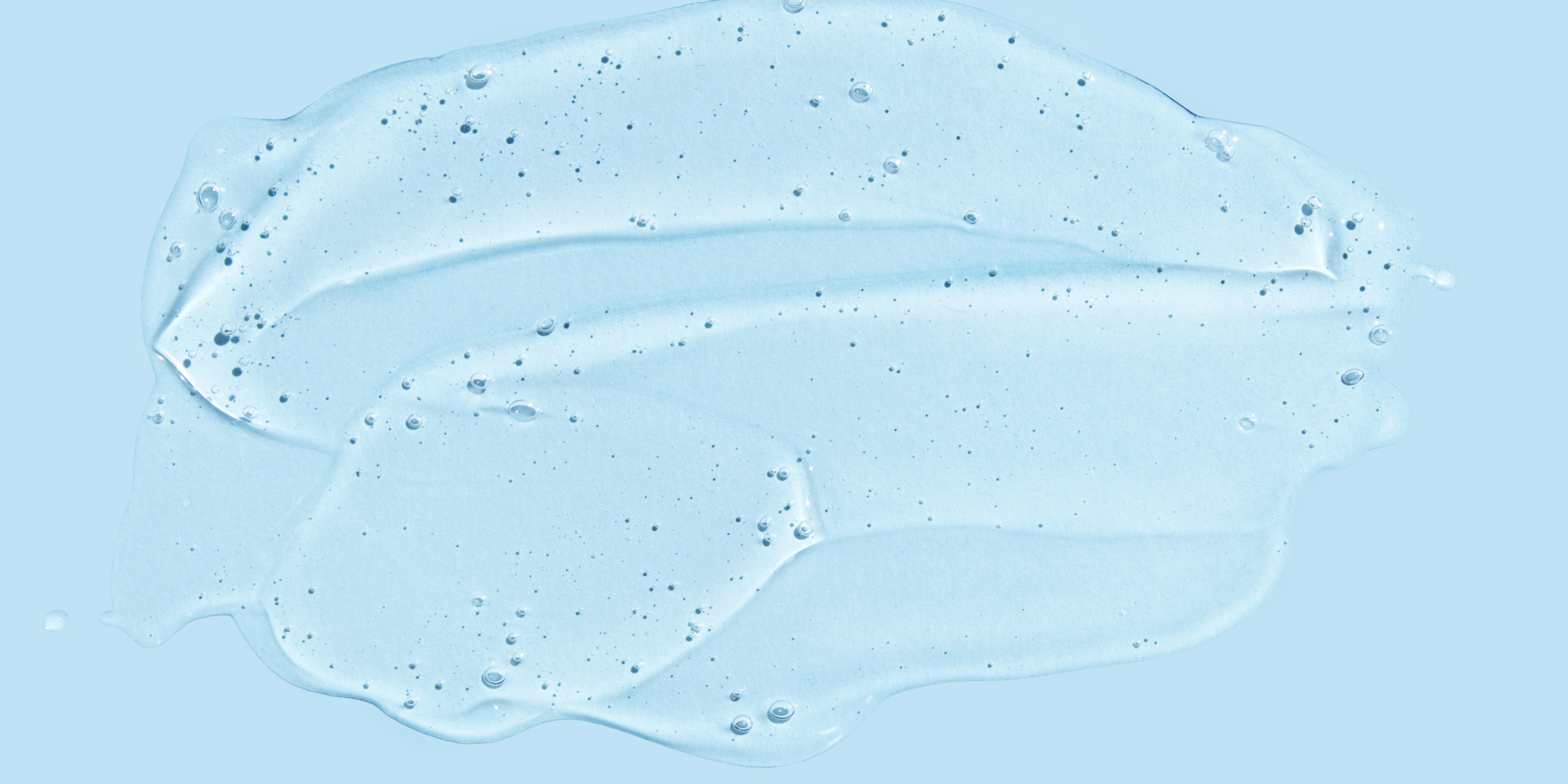 Clear gel or cream with small particles on a light blue background